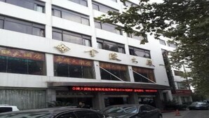A building with multiple floors, large windows, and a sign with Chinese characters. There are cars parked in front. - Jinling Mansion (Nanjing)