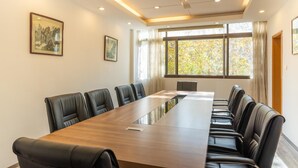 A conference room with a long table and leather chairs, large windows with curtains, and framed artwork on the walls. - Jinling Mansion (Nanjing)