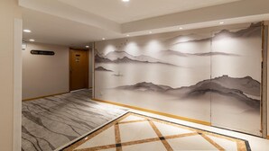 A hallway with a marble floor, a large wall mural depicting mountains, and a door with a sign above it. - Jinling Mansion (Nanjing)