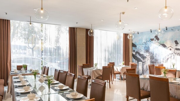 A dining area with multiple tables, chairs, and hanging pendant lights. - Jinling Mansion (Nanjing)