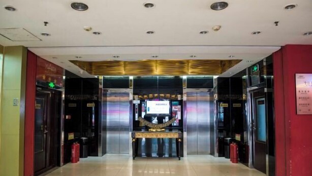 A hotel lobby with a reception desk, elevators, and fire extinguishers. - Yuanda Business Hotel (Harbin)