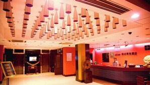 A hotel lobby with a reception desk, multiple hanging light fixtures, and a television screen. - Yuanda Business Hotel (Harbin)