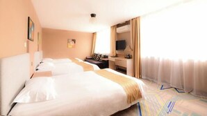 A hotel room with two beds, a desk, a television, and a window with sheer curtains. - Yuanda Business Hotel (Harbin)