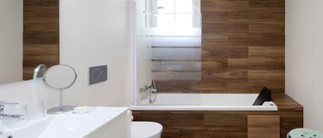 A modern bathroom with a glass-enclosed shower, a white sink, and a toilet.