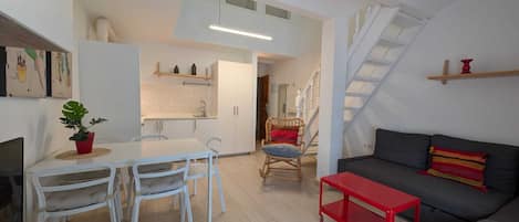 A compact living space with a dining area, kitchenette, and a staircase.