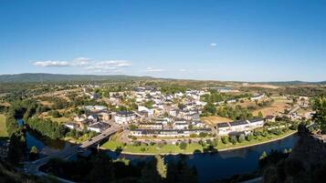 Une vue panoramique d’une ville traversée par une rivière, entourée de verdure et de collines.