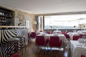Un restaurante con pared de piedra, un sofá estampado con cebra y mesas dispuestas para comer.