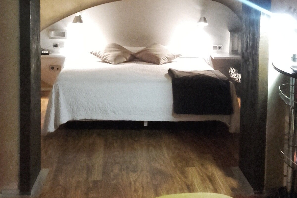 A bedroom with a bed, bedside tables, a nightstand, a lamp, and a chair.