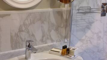 A bathroom with a marble sink, a mirror, a towel bar, and a towel rack.
