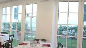 A dining area with tables set for two, large windows, and a view of the outdoors. - Hotel Villa Cappugi (Pistoia)
