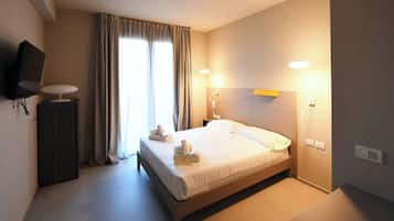 A hotel room with a bed, bedside lamps, a flat-screen TV, and a window with curtains.