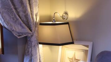 Een hotelkamer met een bed, nachtkastje, lamp, ster decoratie en een parfumflesje.
