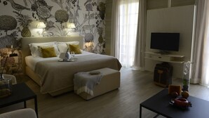 A hotel room with a large bed, bedside lamps, a TV, and a desk with a vase of flowers. - Hotel Villa Cappugi (Pistoia)
