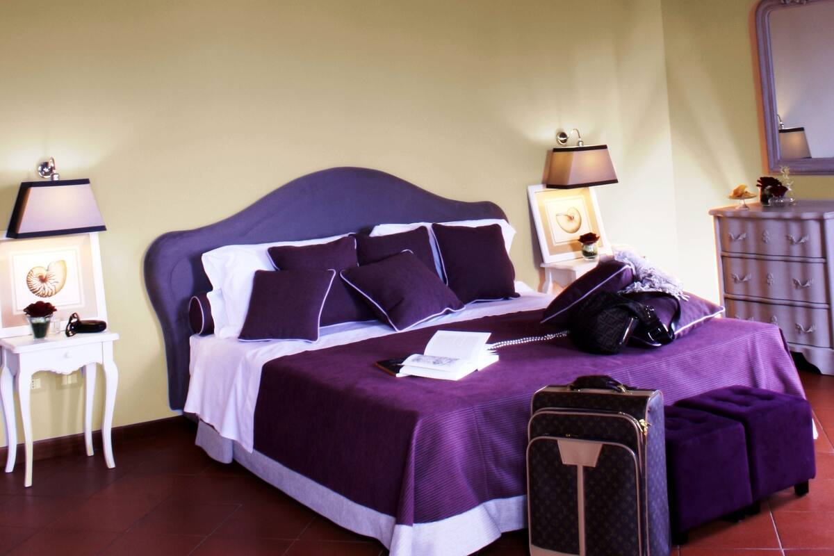 A bedroom with a bed, bedside tables, a dresser, and a suitcase.
