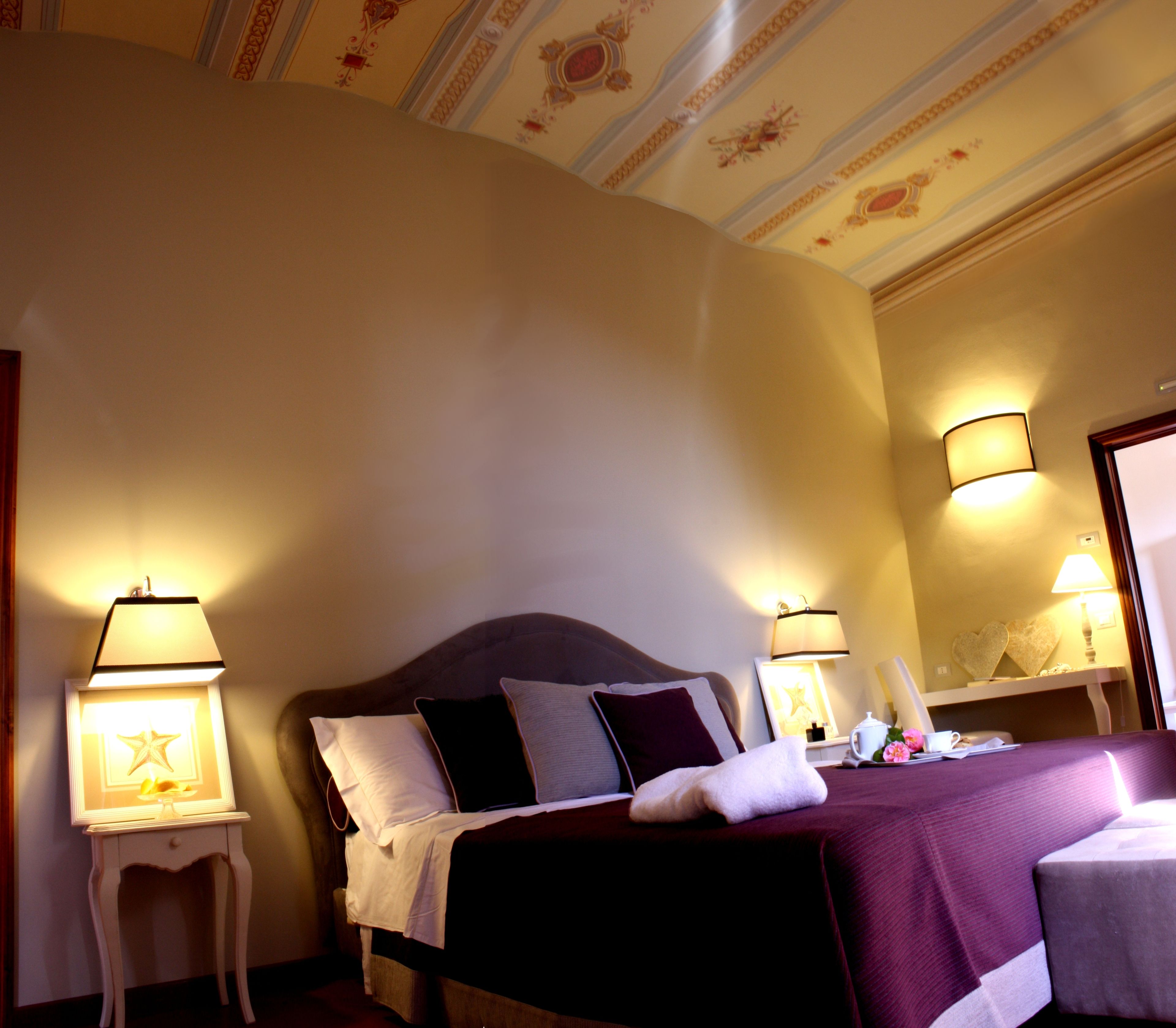 A hotel room with a bed, bedside lamps, a nightstand, and a mirror.