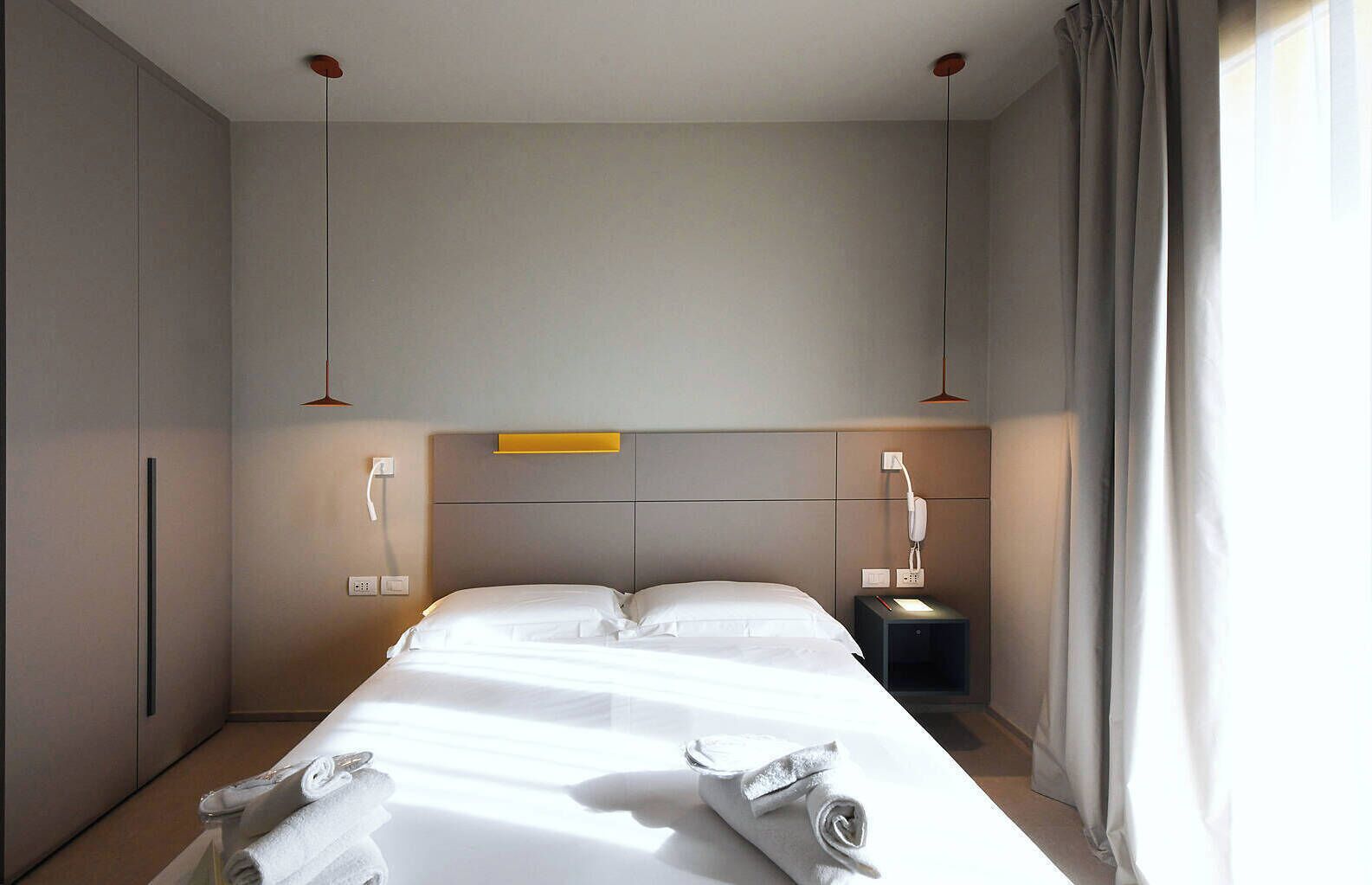 Une chambre d’hôtel moderne dotée d’un grand lit, de tables de chevet et d’une tête de lit avec éclairage intégré.