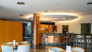 Een moderne bar met ronde tafels en barstoelen, een centrale pilaar en een toonbank met een menu.