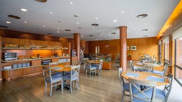 Un restaurant moderne avec un plancher en bois, des tables rondes et des chaises rembourrées de couleur bleue.