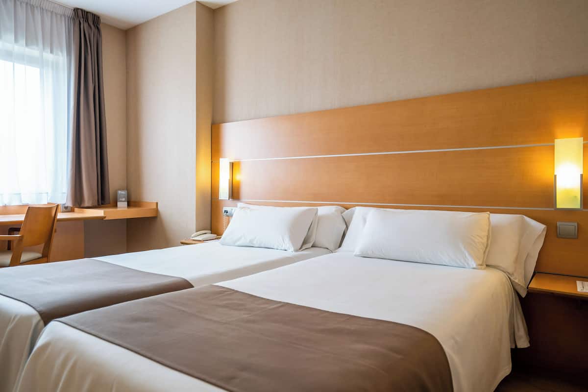 Une chambre d’hôtel avec deux lits, un bureau et une chaise.