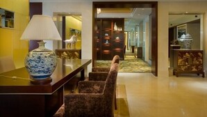 A lobby with a marble floor, a reception desk, a sofa, a lamp, and a display of decorative items. - Grand Soluxe International HOT (Xi'an)