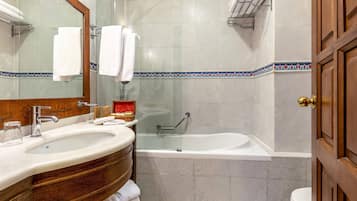 A bathroom with a sink, mirror, bathtub, and toilet.