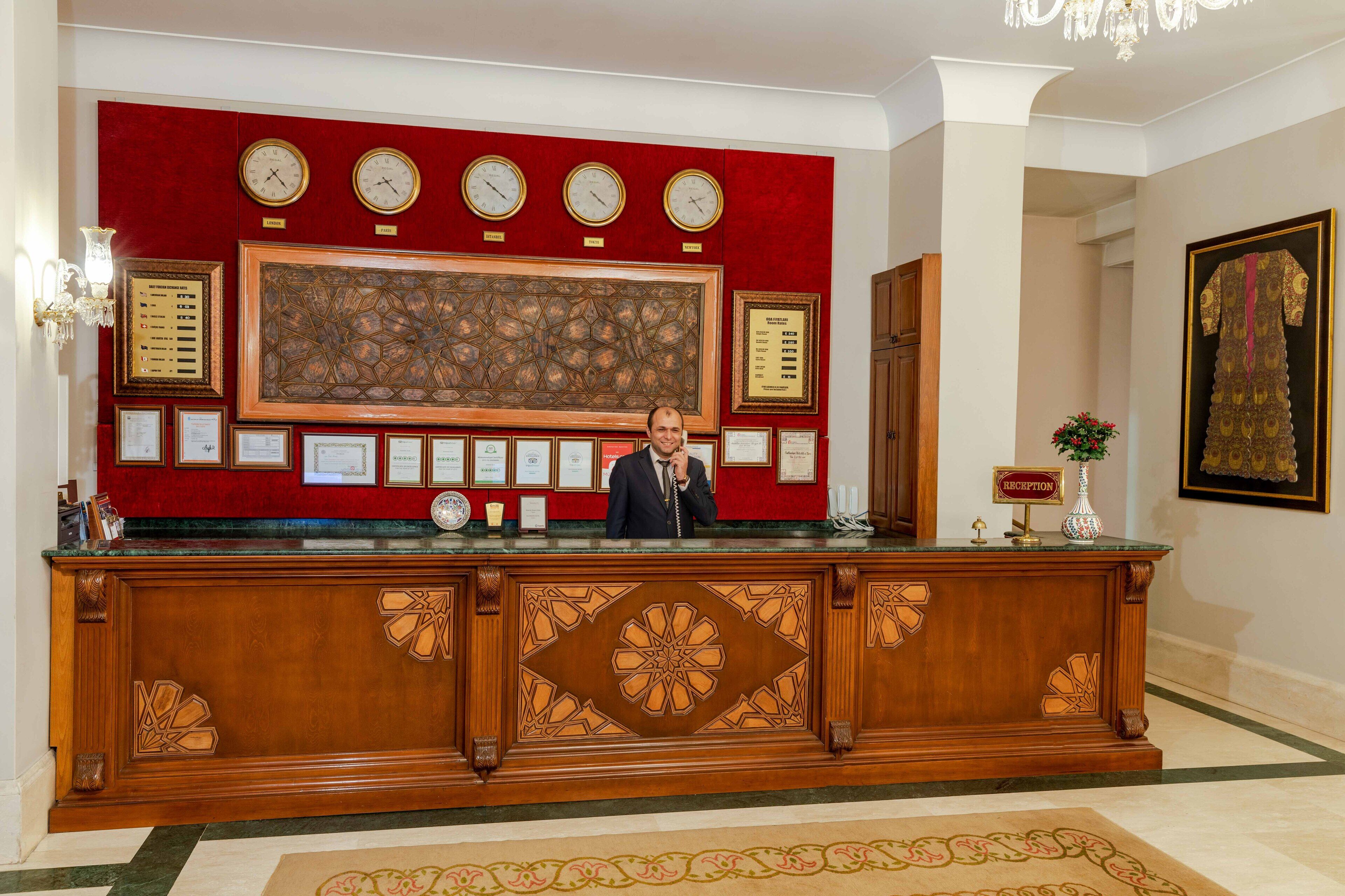 Mostrador de recepción con un reloj, diplomas enmarcados y una recepcionista.