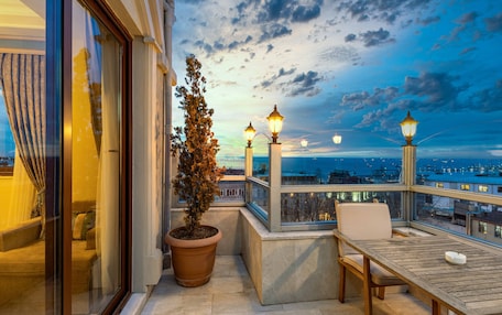 A balcony with a potted plant, a table, and two chairs.