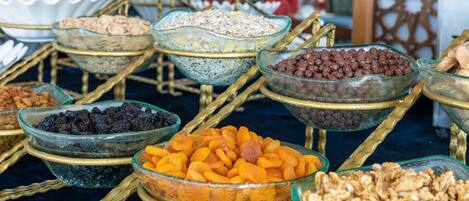 Um buffet com diversos alimentos dispostos em recipientes de vidro sobre suportes dourados.