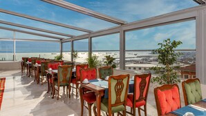 Un espace repas offrant une vue sur la plage et l’aéroport.