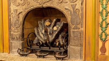 Una chimenea de piedra con intrincados grabados y una repisa con tres candelabros metálicos.
