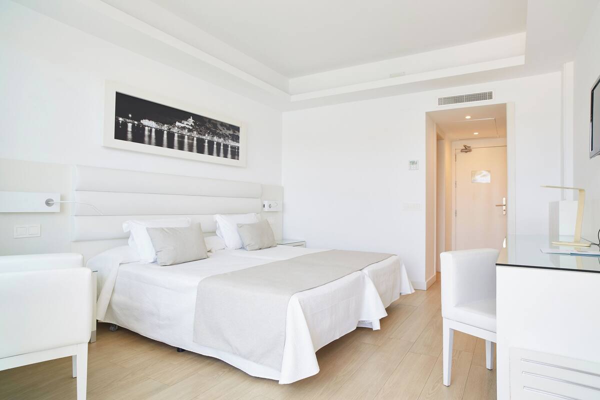 A modern hotel room with a large bed, a desk, and a chair.