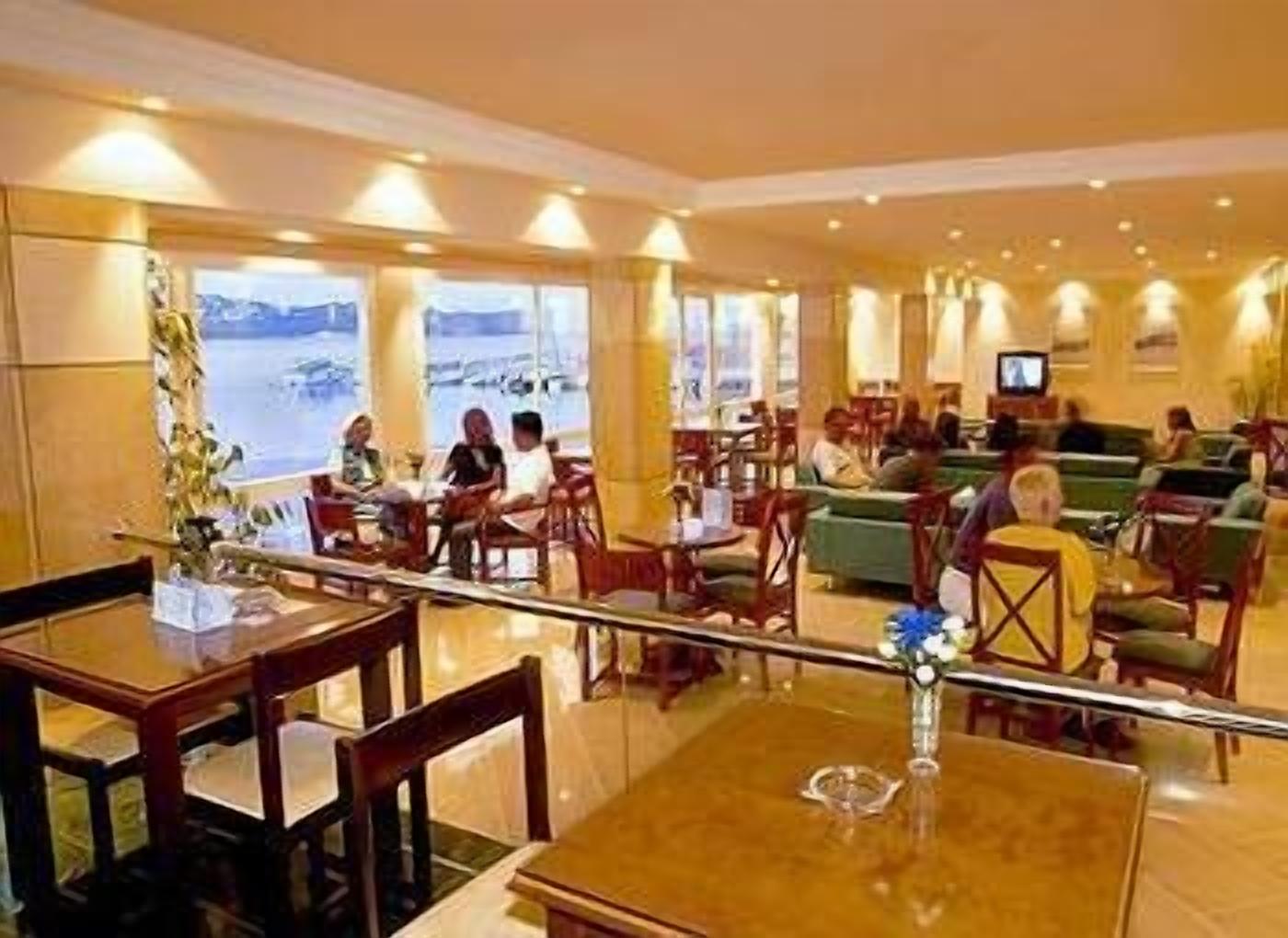 A hotel lobby with a seating area, a dining section, and a view of the sea.