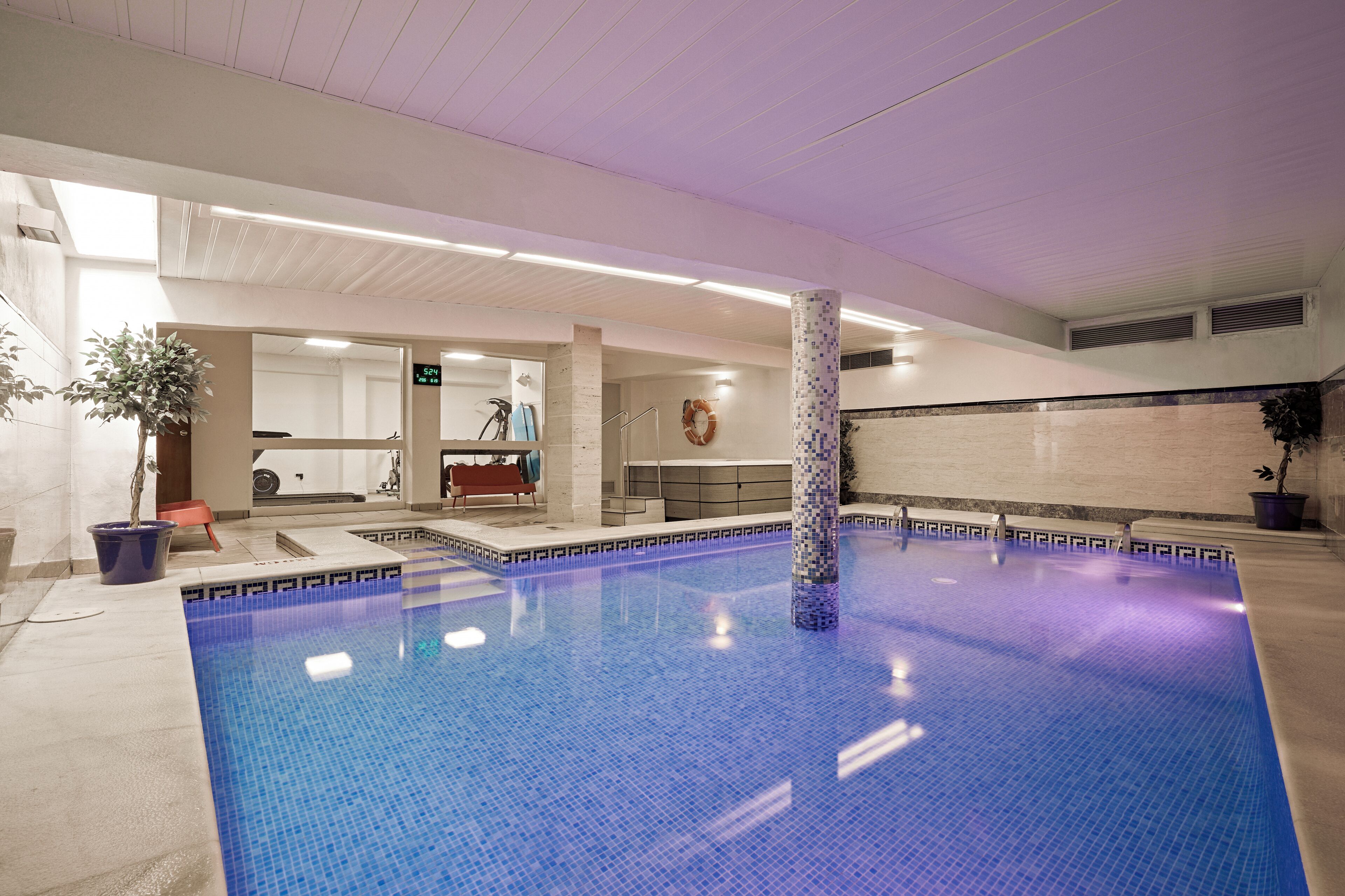 An indoor swimming pool with a tiled floor and a central pillar.