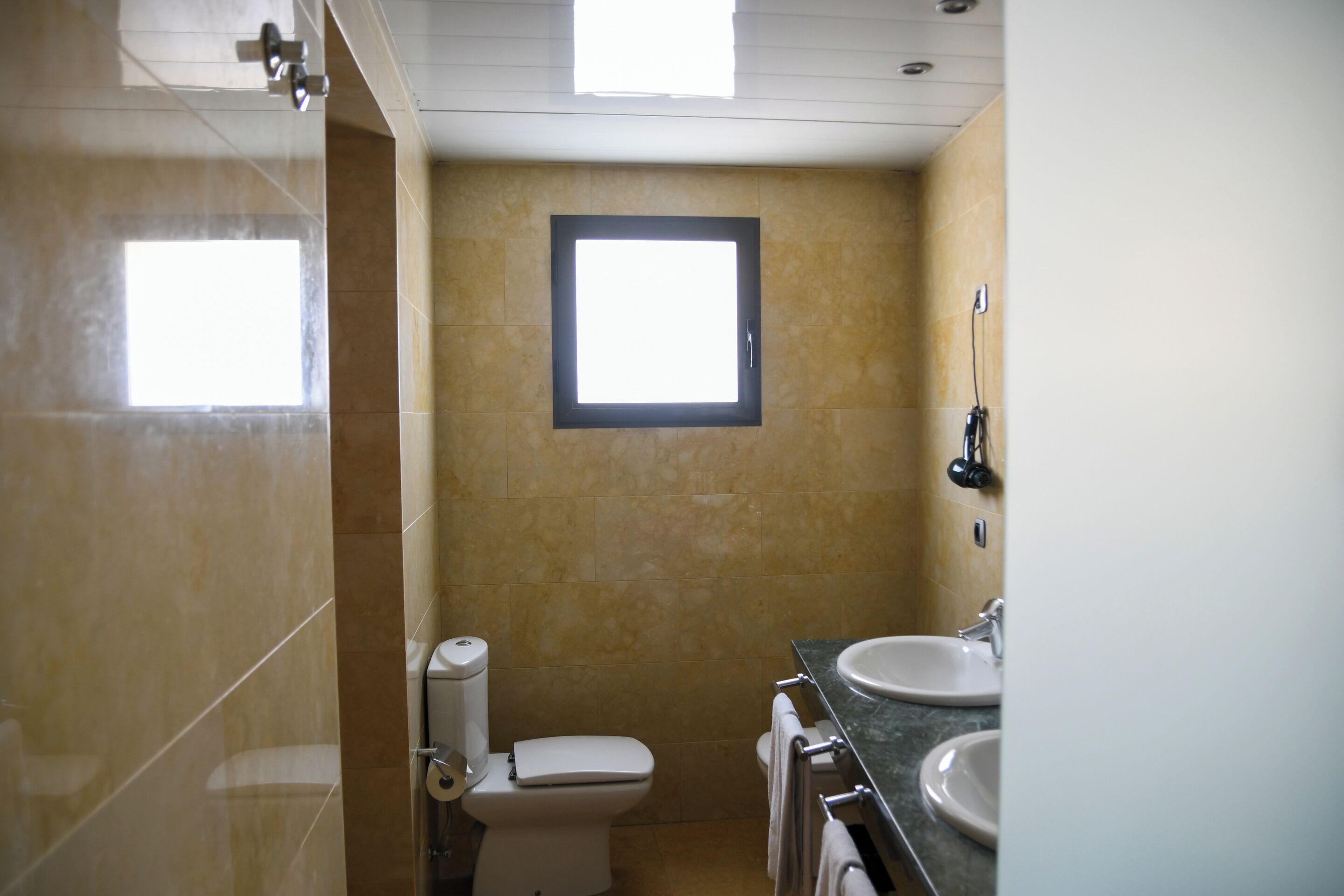 Une salle de bain avec des toilettes, un lavabo et une fenêtre.