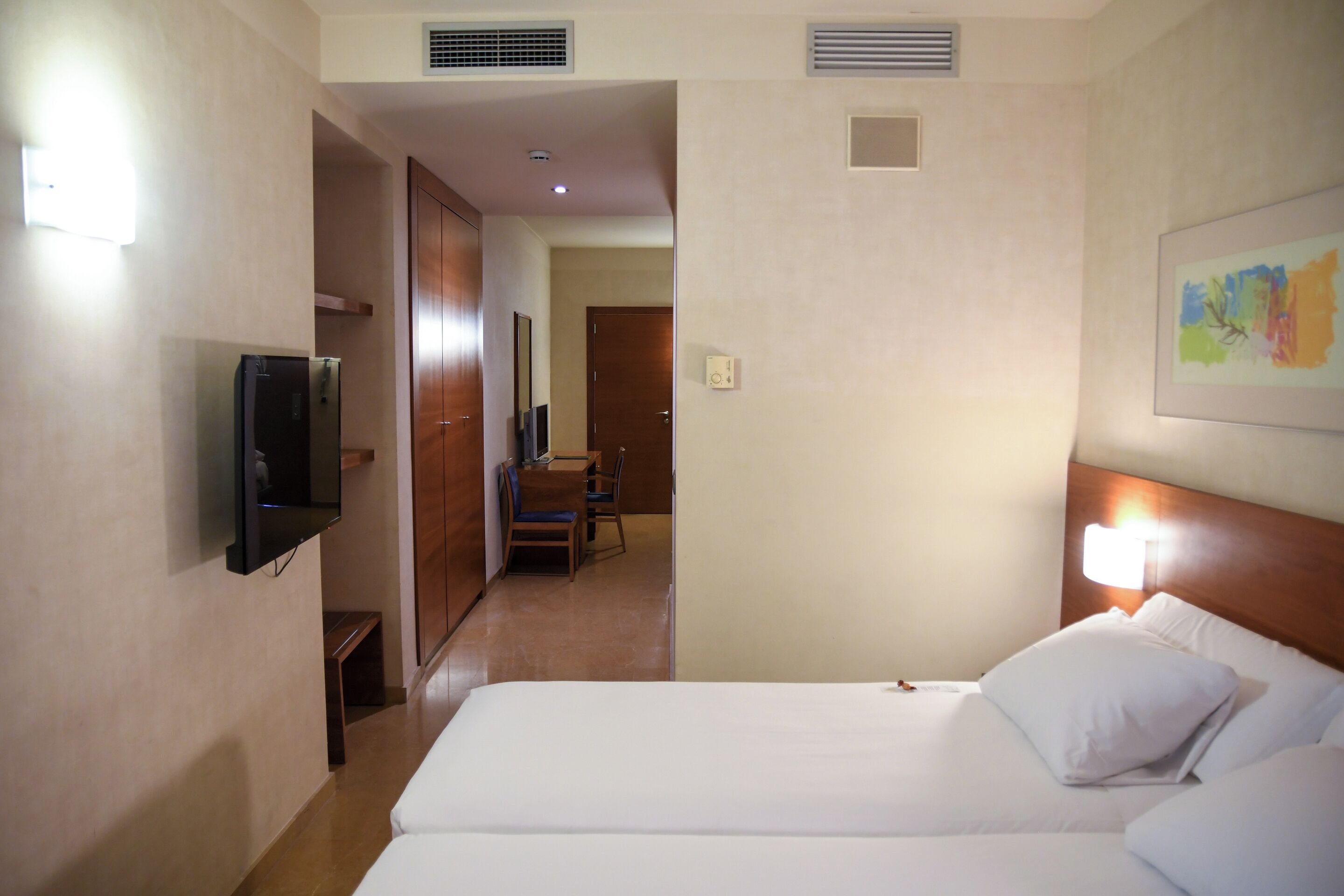Une chambre d’hôtel avec deux lits, une télévision, un bureau et une chaise.