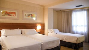Een hotelkamer met twee bedden, een houten hoofdeinde en kunst aan de muur.