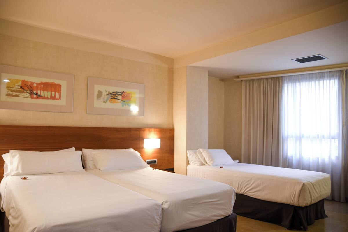 A hotel room with two beds, a wooden headboard, and artwork on the wall.