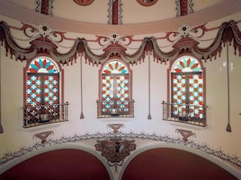 Un salón imponente con arcos decorados y vidrieras de colores.