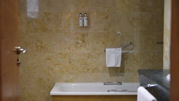 A bathroom with a bathtub, a toilet, and a shower area.