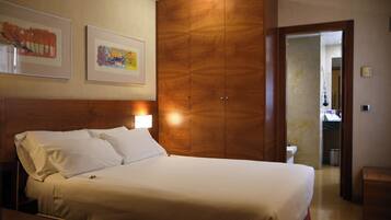 Una habitación de hotel con una cama grande, un armario de madera y dos cuadros enmarcados en la pared.