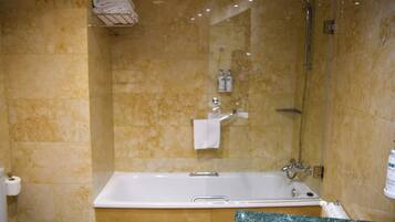 A bathroom with a bathtub, a glass-enclosed shower, and a marble countertop.