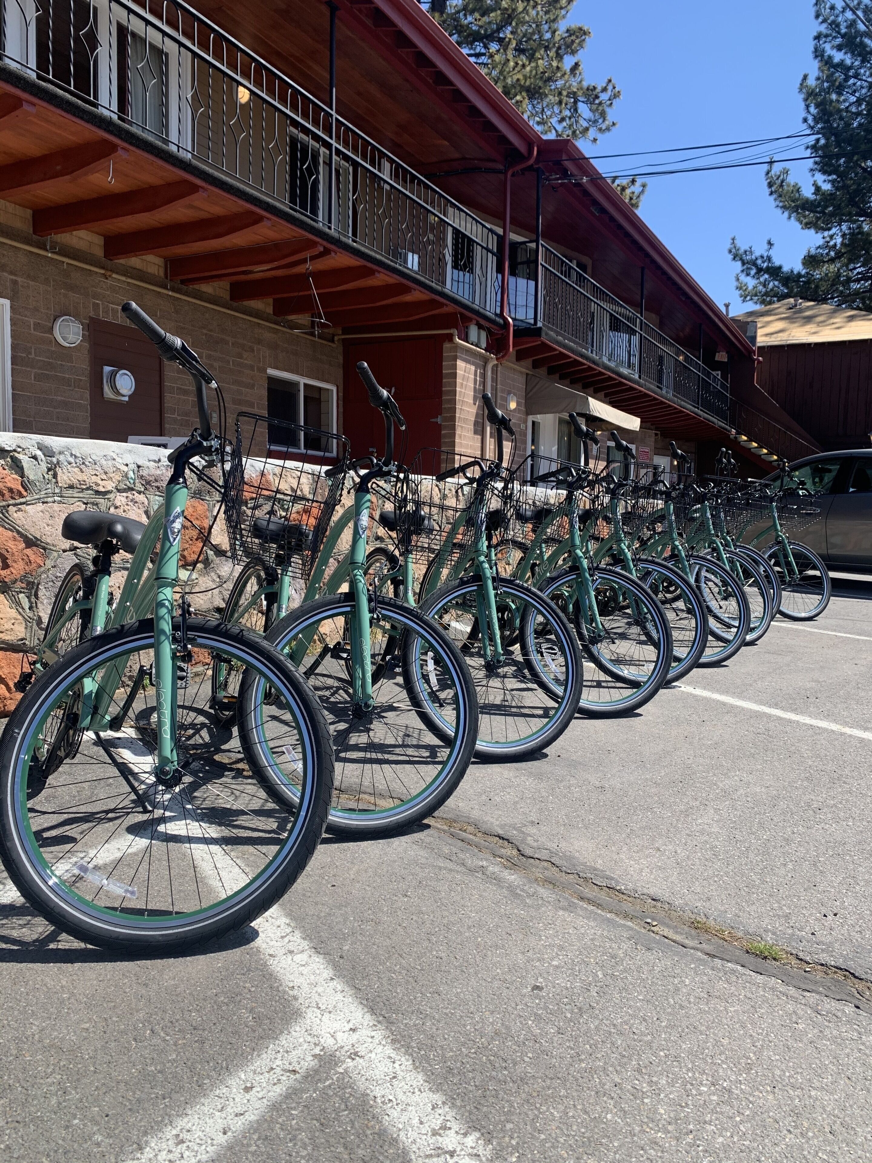 Une rangée de vélos est stationnée dans un espace prévu à cet effet, devant un bâtiment à la façade en bois et doté d’un balcon.