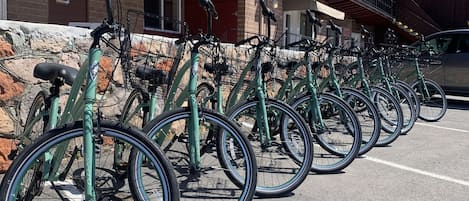 Une rangée de vélos est stationnée dans un espace prévu à cet effet, devant un bâtiment à la façade en bois et doté d’un balcon.