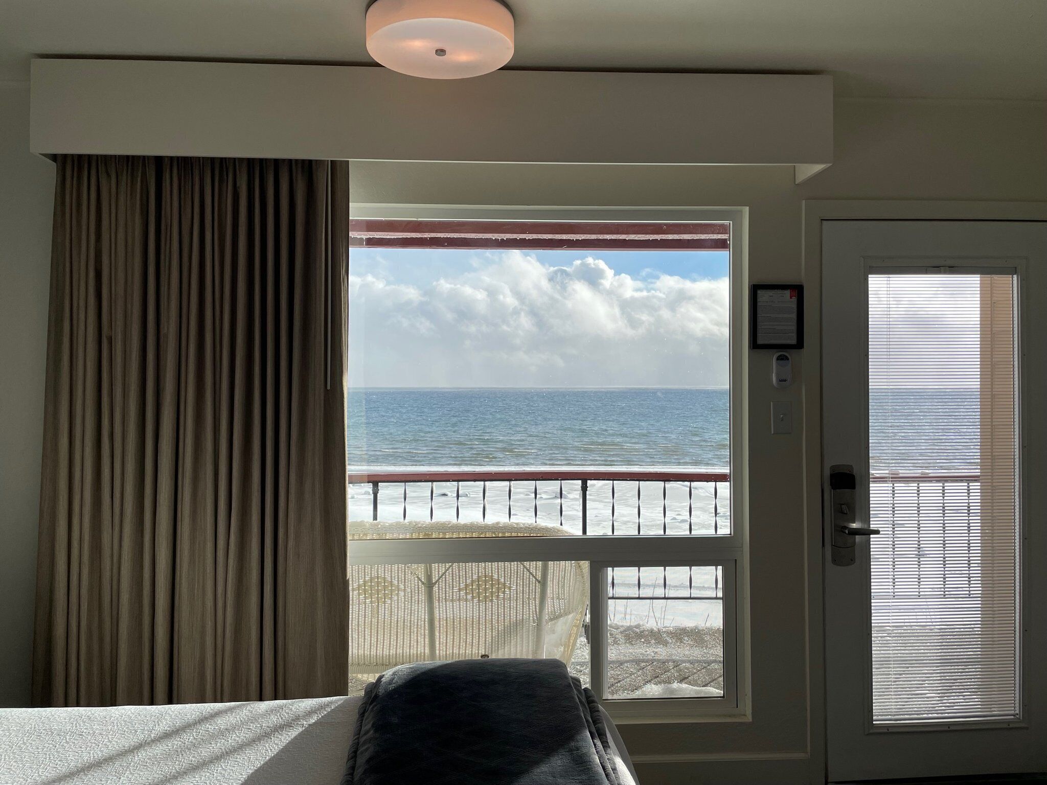Ein Zimmer mit Blick auf das Meer, ein Fenster, eine Tür mit Fenster und ein Vorhang.