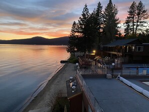 A waterfront property with a beach, a covered patio, and a building with a deck.
