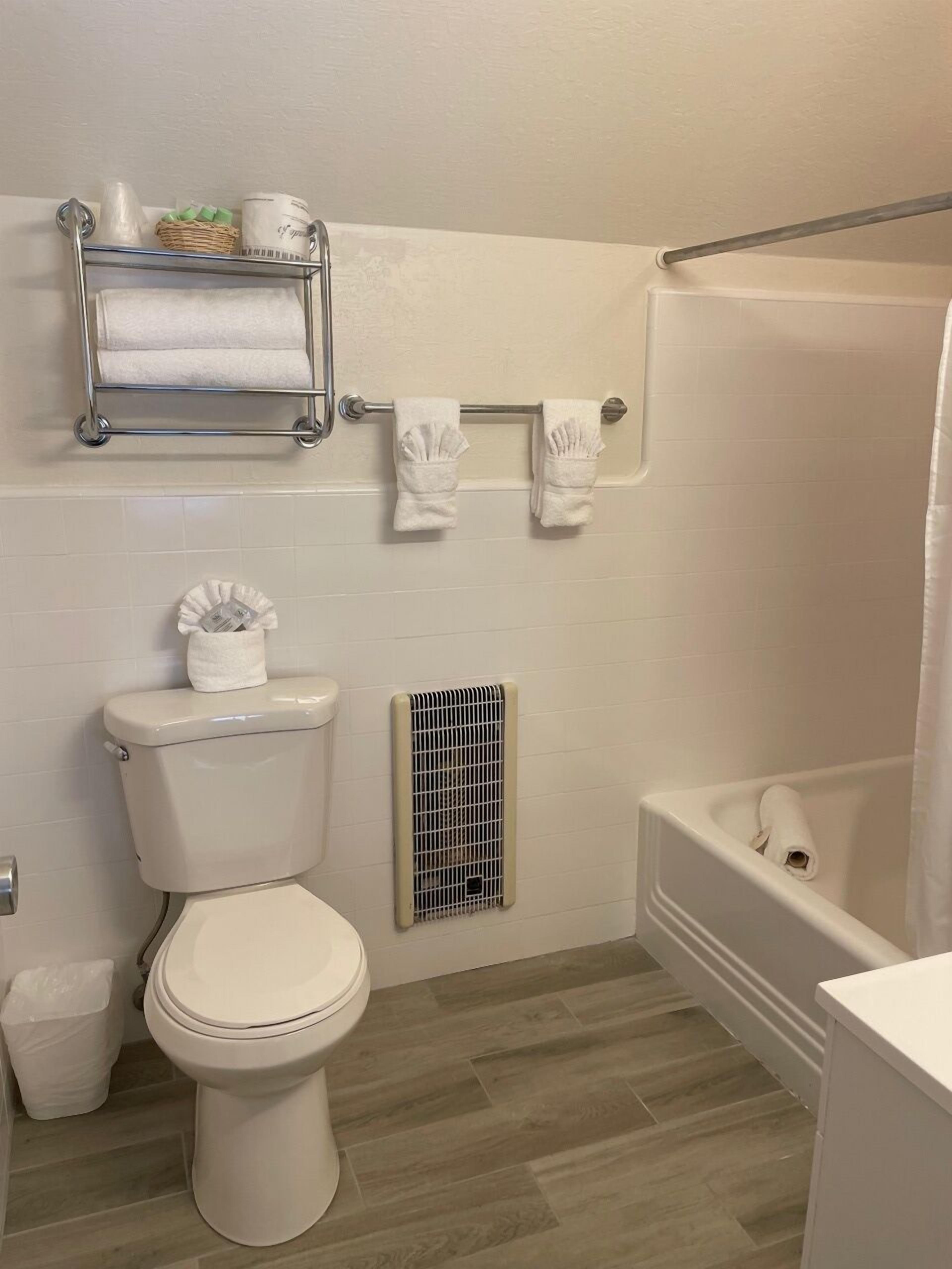 Un baño con inodoro, ducha y toallero con toallas.