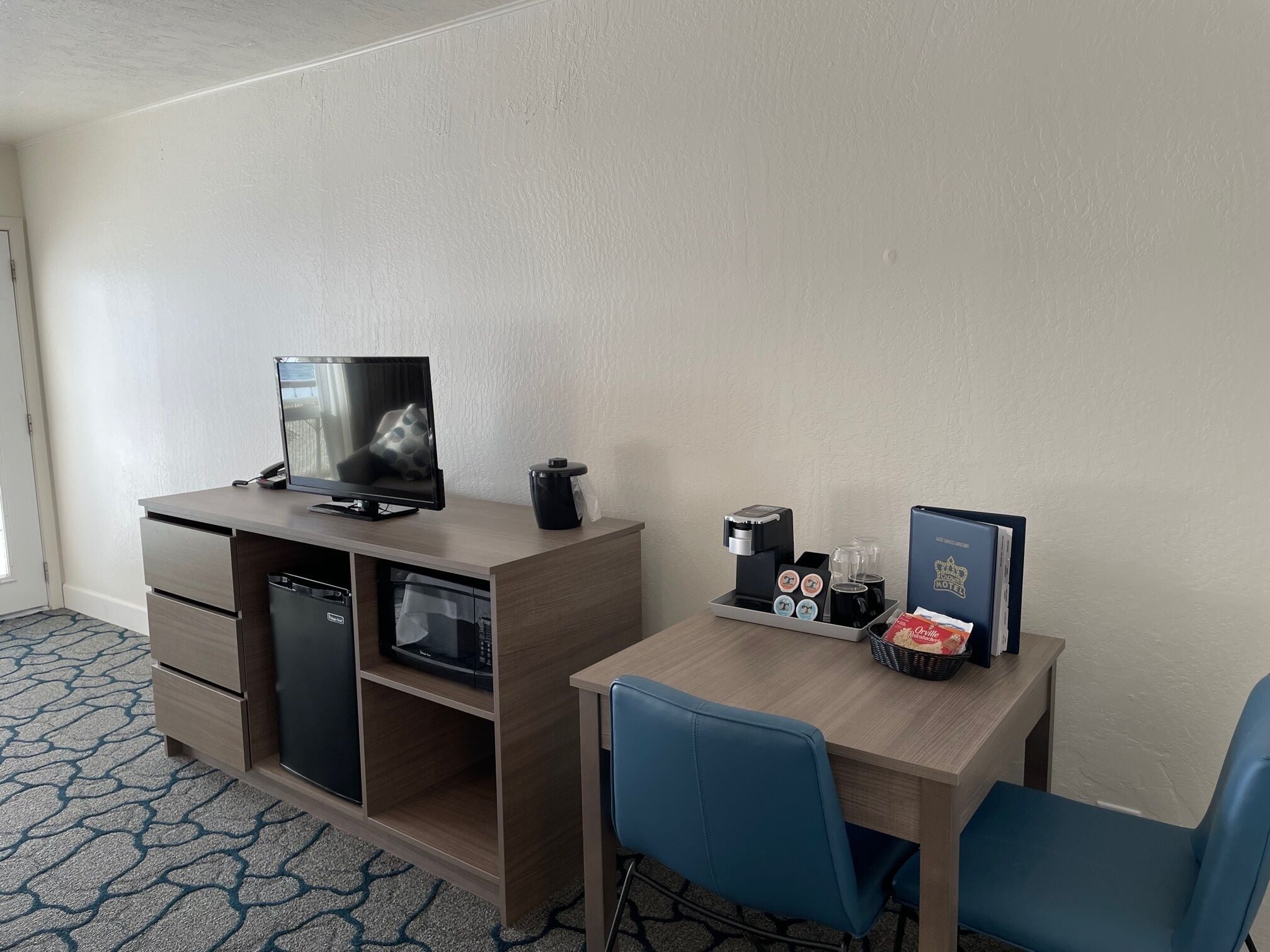 Une chambre d’hôtel équipée d’un bureau, d’une télévision, d’une machine à café, d’un four à micro-ondes et d’une bibliothèque.