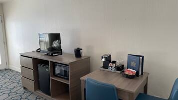 Une chambre d’hôtel équipée d’un bureau, d’une télévision, d’une machine à café, d’un four à micro-ondes et d’une bibliothèque.