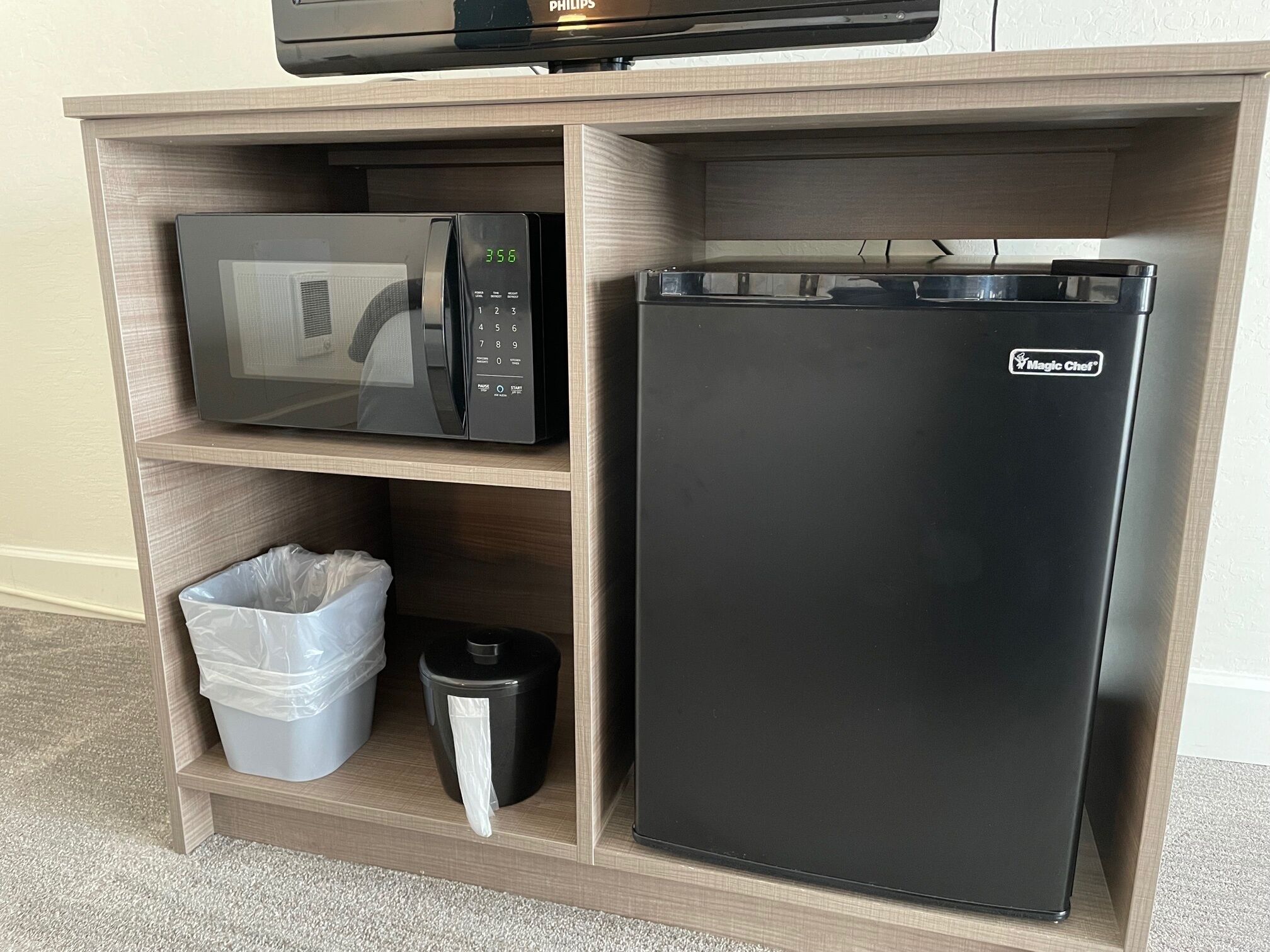 Una kitchenette equipada con microondas, refrigerador y basurero.