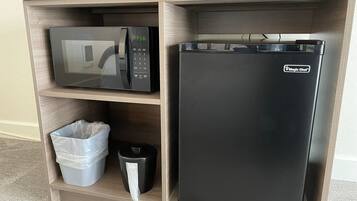 Una kitchenette equipada con microondas, refrigerador y basurero.